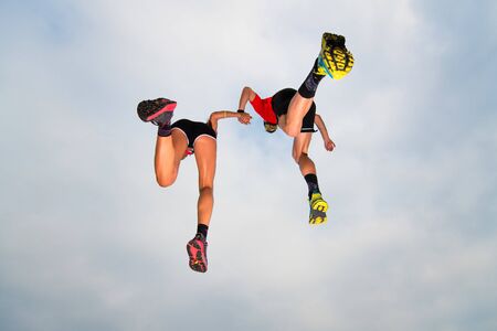 Pair of sportsmen make a jump in the sky hand in handの写真素材