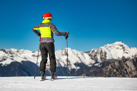 On the ski slopes of a ski area, a skier looks at the mountains before skiingの写真素材