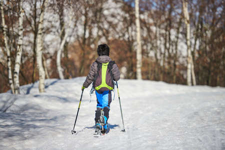 Little child with touring skis in snowy roadの写真素材