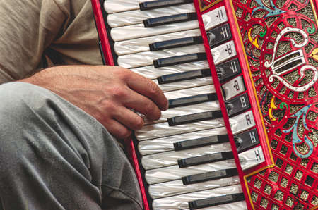 Detail of fingers on the keyboard of the red accordionの写真素材