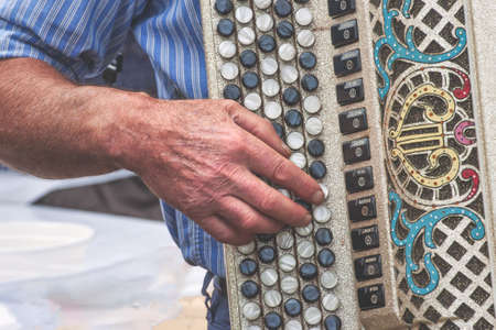 Hand detail of elderly person playing chromatic accordion at a folk festivalの写真素材