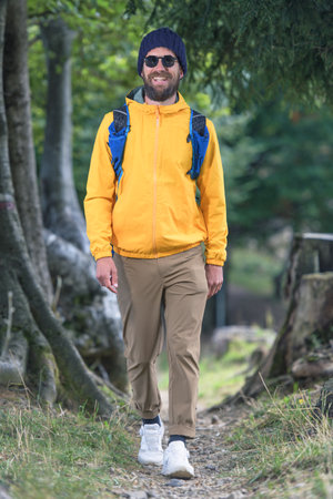 Young sporty man smiles walks on nature trail