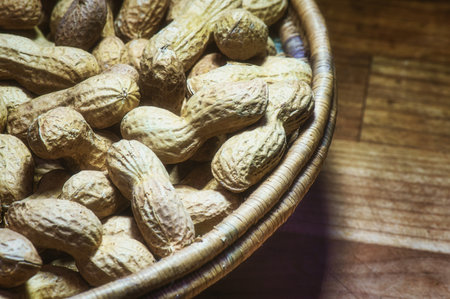 Peanuts in natural bowl resting on wooden table