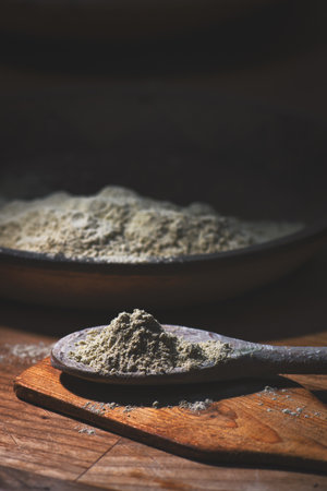 Green clay in wooden spoon on a tableの写真素材
