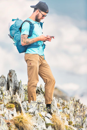 A young sportsman handles smartphone during in alpine trekkの写真素材