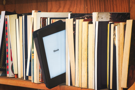 Wooden bookcase with e book reader amid classic books