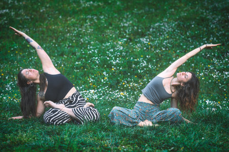 Couple of friends practice meditative yoga in a spring flower meadow