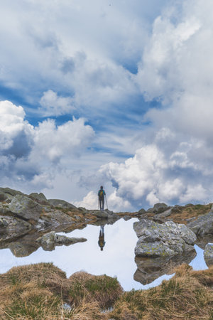 A distant person observes the sky near a small mountain lakeの写真素材