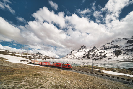 Red train of the Swiss Alps in the spring thaw under the Bernina passの写真素材