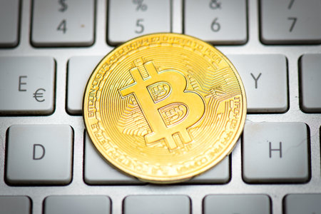 Bitcoin coin on computer keys on white background