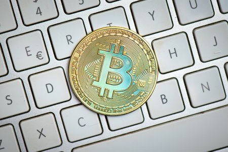 Bitcoin coin resting on the computer keyboard on white background