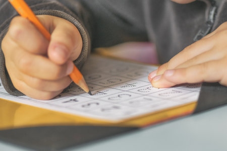 The pencil in the hands of a child at school