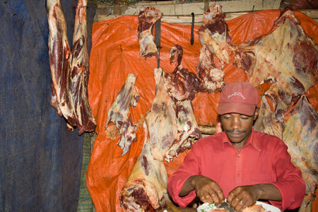 DORZE, ETHIOPIA - JANUARY 1, 2009  Butcher eats with hands in his typical butcher shop on January 1, 2009 in Dorze, Ethiopia のeditorial素材