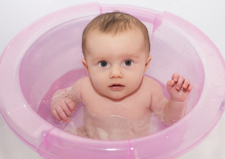 Close up of little baby who makes a bath in the pink tub.の写真素材