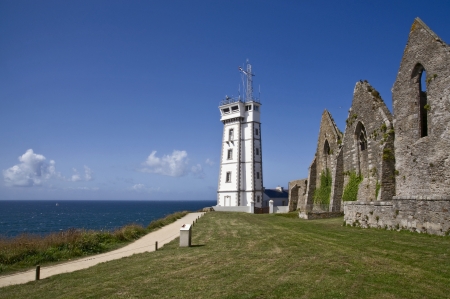 Saint Mathieu lighthouse by the coast in Britain with clouds and stone beach の写真素材