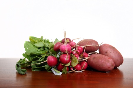 fresh radishes and potatoes on a wooden board