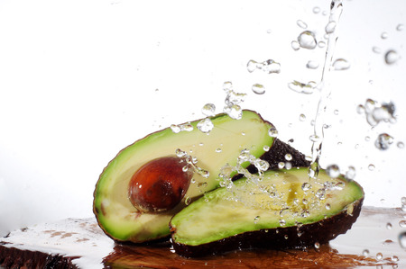 avocado on a wooden board with splash waterの写真素材