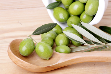 Wooden spoon and green olivesの写真素材