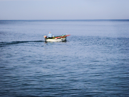 Lonely fisherman in a wooden boat