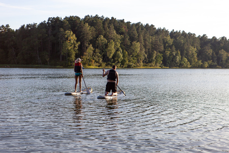 Stand up paddle boarding sup on a quiet lake with warm summer sunset colors