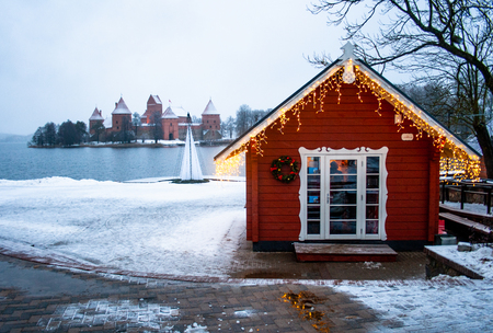 Frozen lake, a small wooden house with lights on a lake in Trakai, Vilnius, Lithuaniaの写真素材