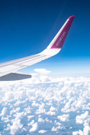 Wizzair logo or brand on the wing, blue sky with cloudsのeditorial素材