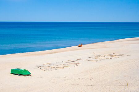 Beautiful sandy beach with dunes in Nida - Curonian Spit and Baltic Sea, Nida, Klaipeda, Lithuania, Unesco heritage with boat and people on the shoreの写真素材