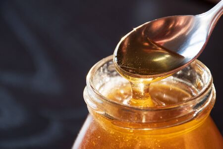 Delicious organic natural honey pours out of a glass jar. Stock photography Delicious organic...