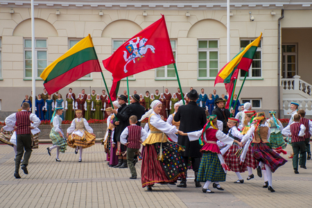 Vilnius / Lithuania - July 6 2019: Dancers dancing traditional old dances with traditional folk costumes in front of the President Palace with Lithuanian flag and flag during a national ceremonyのeditorial素材