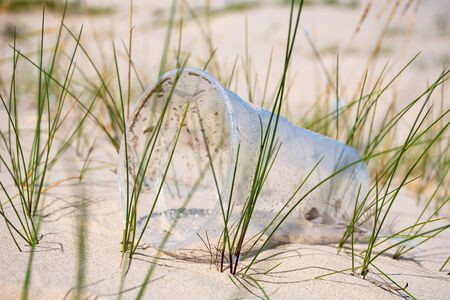 RRubbish plastic disposable cup on sandy beach, plastic pollution