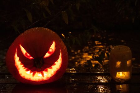 Spooky Halloween pumpkins, Jack O Lantern, with burning candles, and river on backgroundの写真素材