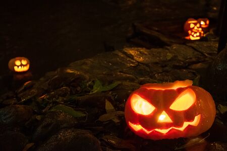 Spooky Halloween pumpkins, Jack O Lantern, with burning candles, and river on background