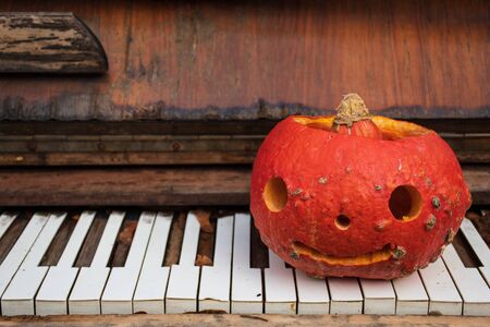 Spooky Halloween pumpkin, Jack O Lantern on the keyboard of an old grand pianoの写真素材