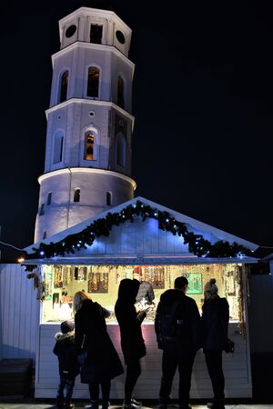 Christmas market with lights, Vilnius Cathedral square with stands or stalls, with tower on the background, verticalの写真素材