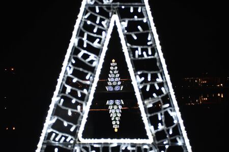 Christmas tree in a triangle of lights at night