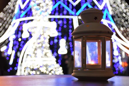 Lantern with candle and Christmas lights on the backgroundの写真素材