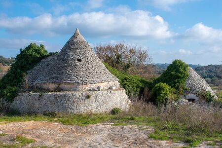 Ancient Trulli, traditional old house and old stone wall in Puglia, Italy, Europe with olive treesのeditorial素材