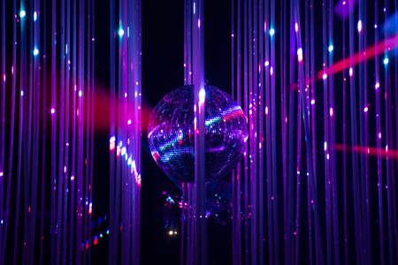 Dance floor disco night with a mirror ball symbol of fun and party in a nightclub or dance club with glowing stage lights and reflections, blue, violet, purpleの写真素材