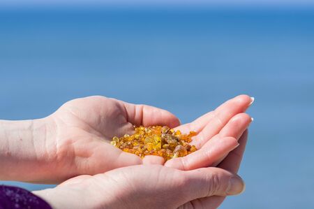 Beautiful pieces of amber in the hand of a girl with blue sky backgroundの写真素材