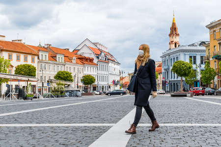 Beautiful blond girl with mask walking in the city center during quarantine days