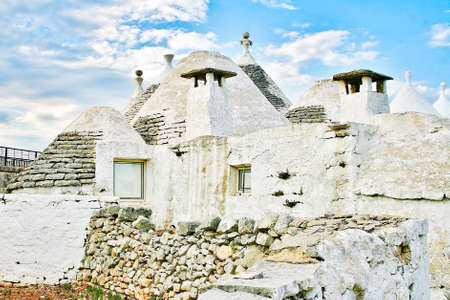 Group of beautiful white Trulli, traditional Apulian dry stone hut old houses with a conical roof in Itria Valley, Puglia, Italyの写真素材