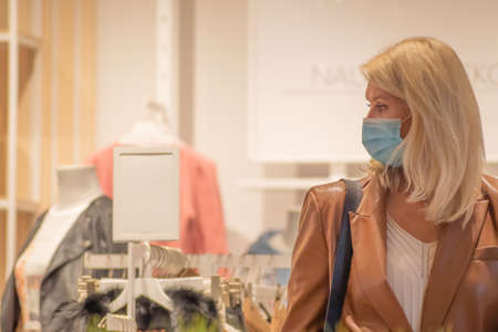 Beautiful blonde hair girl in a shop with mask, shopping during Covid or Coronavirus outbreak, new...