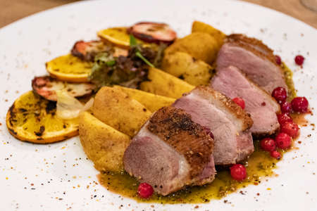 Dish of duck breast steak with caramelized fruit, orange, mango, apple, lingonberry, sauce of orange...