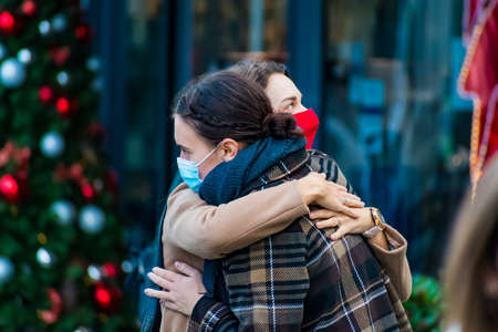 Vilnius, Lithuania - November 11 2020: Girls wearing masks, meeting and hugging for greetings during...