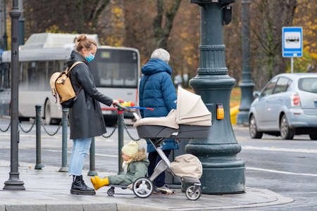 Vilnius, Lithuania - November 6 2020: Girl with stroller walking in the city near a shop or shopping center during Covid or Coronavirus outbreakのeditorial素材