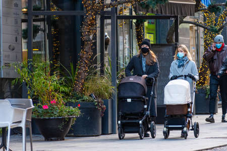 Vilnius, Lithuania - November 22 2020: Girls wearing protective face mask with stroller walking in...