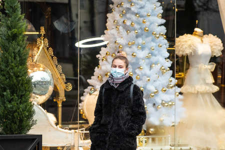 Vilnius, Lithuania - November 22 2020: Beautiful blond girl wearing mask and walking in the city...