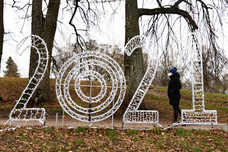 Trakai, Vilnius, Lithuania - December 5 2020: Happy New Year 2021, letters and numbers with girl wearing mask and walkingのeditorial素材