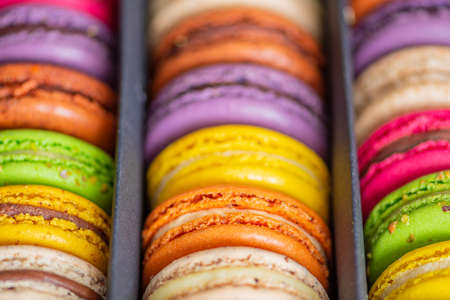 Various colorful macarons or French macaroons in a row in a gift box, sweet meringue-based confection made with egg white, icing sugar, granulated sugar, almond meal, and food coloring, close upの写真素材