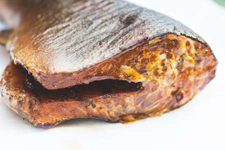 Piece of smoked spiced salmon or trout fish ready to eat in a plate, close upの写真素材
